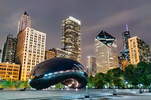 The Cloud Gate sculpture at night reflects the light of nearby buildings.
