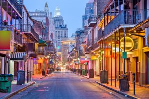 A view of a street in the French Quarter of New Orleans with colorful lighting.