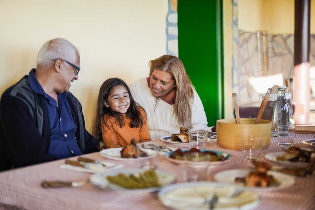 A man, woman, and young girl sitting at a table with food.